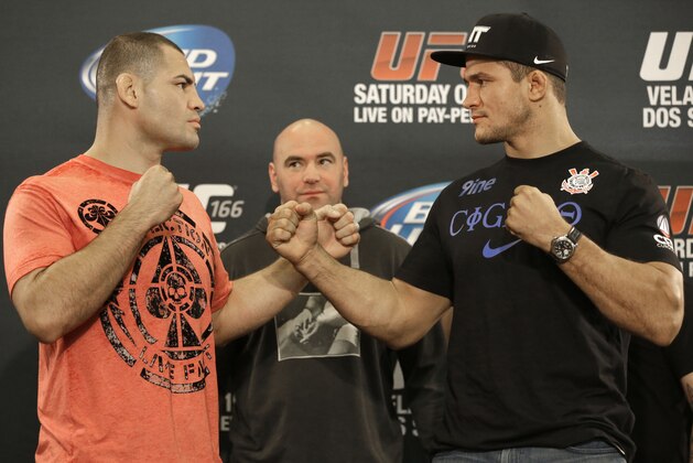 UFC heavyweight champion Cain Velasquez, left, and former heavyweight champion Junior Dos Santos, right,  face off with UFC president Dana White between them following a media availability Thursday, Oct. 17, 2013, in Houston. Velasquez will fight Santos in a rematch in Houston Saturday. He beat Santos in a five-round decision in December to regain the title after Santos won in a knockout in the first meeting in 2011. (AP Photo/Pat Sullivan)