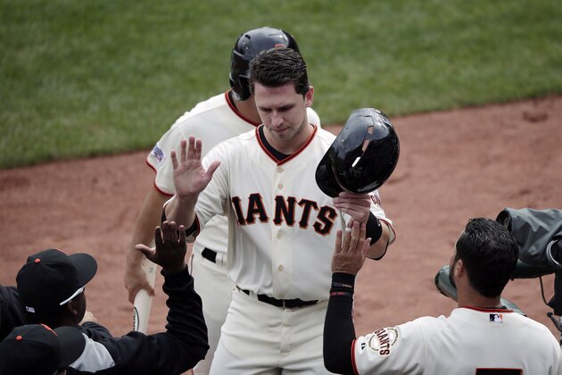 San Francisco Giants' Buster Posey is greeted by teammates after scoring on a double by Hunter Pence during the first  inning of Game 3 of the National League baseball championship series against the St. Louis Cardinals, Tuesday, Oct. 14, 2014, in San Francisco. (AP Photo/Marcio Jose Sanchez)
