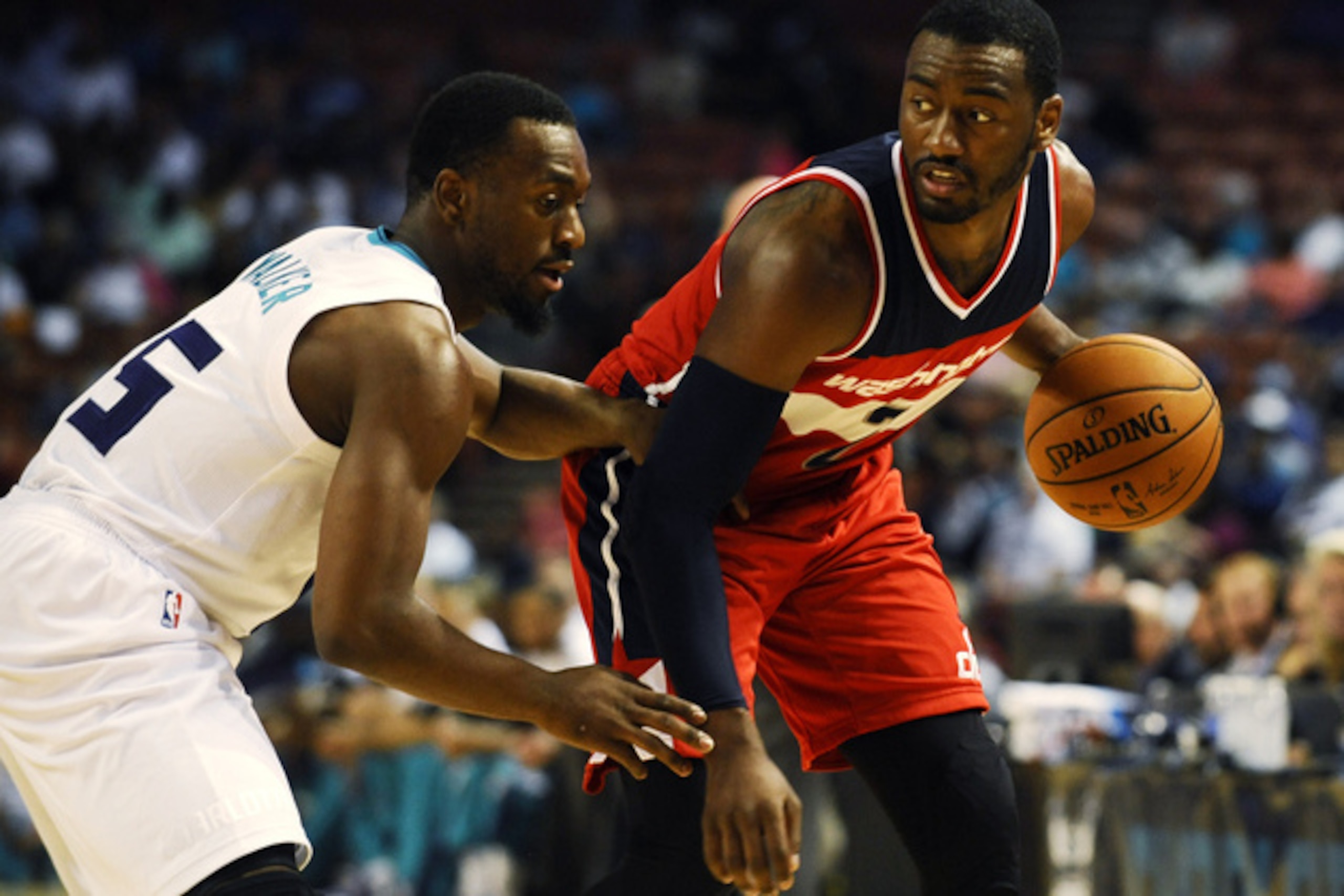 Washington Wizards guard John Wall (2) looks to pass as Charlotte Hornets guard Kemba Walker (15) defends during the first half of a preseason NBA basketball game, Friday, Oct. 10, 2014, in Greenville, S.C. Charlotte won 99-86. (AP Photo/Rainier Ehrhardt)