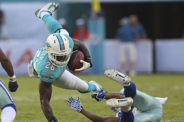 MIAMI GARDENS, FL - AUGUST 23:  Lamar Miller #26 of the Miami Dolphins is upended by Orlando Scandrick #32 of the Dallas Cowboys in the first quarter during a preseason game at Sun Life Stadium on August 23, 2014 in Miami Gardens, Florida.  (Photo by Mike Ehrmann/Getty Images)
