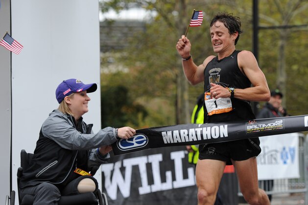 Boston marathon bombing survivor Erika Brannock holds an end of the tape at the finish line as runner David Berden wins the Baltimore marathon on Saturday, Oct. 12, 2013. (AP Photo/Gail Burton)