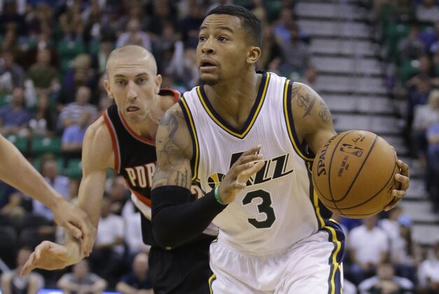 Utah Jazz's Trey Burke (3) brings the ball up court as Portland Trail Blazers' Steve Blake, rear, pursues in the fourth quarter during an NBA preseason basketball game Tuesday, Oct. 7, 2014, in Salt Lake City. (AP Photo/Rick Bowmer)