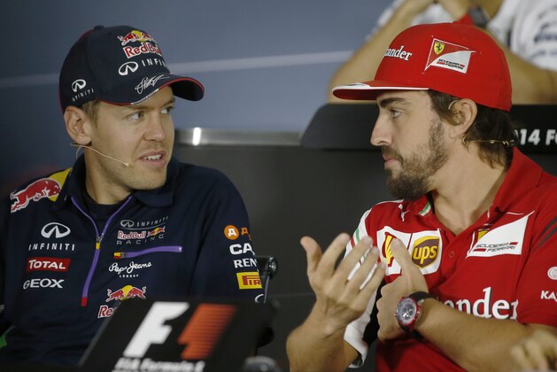 Ferrari driver Fernando Alonso of Spain, right, talks with Red Bull driver Sebastian Vettel of Germany during a news conference at the Sochi Autodrom Formula One circuit in Sochi, Russia, Thursday, Oct. 9, 2014. Formula One drivers say they will race this weekend's Russia Grand Prix for Jules Bianchi, who was seriously injured in an accident last week in Japan.Four-time defending Formula One champion Sebastian Vettel will leave Red Bull at the end of the season and is expected to soon announce a deal with Ferrari. The inaugural Russian GP will be held on Sunday in Sochi, the Black Sea resort that hosted this year's Winter Olympics. (AP Photo/Luca Bruno)