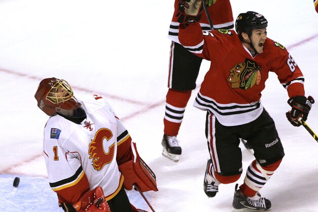 Chicago Blackhawks center Andrew Shaw, right, celebrates after scoring a goal as Calgary Flames goalie Jonas Hiller (1) reacts during the third period of an NHL hockey game in Chicago, Wednesday, Oct. 15, 2014. The Flames won 2-1 in overtime. (AP Photo/Nam Y. Huh)