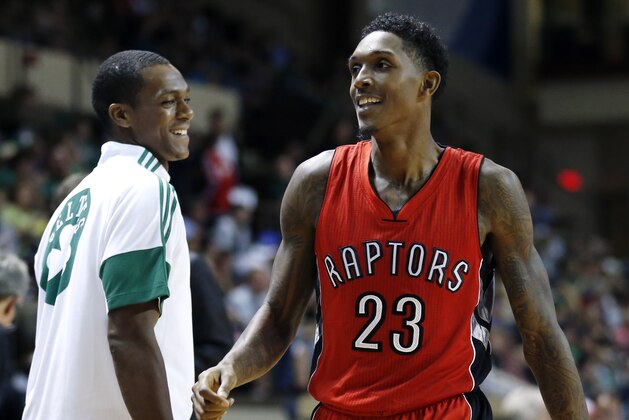 Toronto Raptors guard Louis Williams (23) smiles with Boston Celtics guard Rajon Rondo, who was on the bench with a broken hand, in the second half of a preseason NBA basketball game in Portland, Maine, Wednesday, Oct. 15, 2014. The Raptors won 92-89. (AP Photo/Elise Amendola)