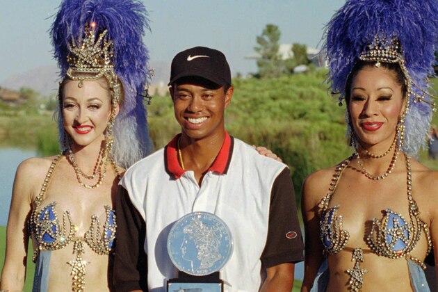 Tiger Woods, center, poses with Ballys' Jubilee dancers Windi See, left, and Gracie Martinez after winning his first pro tournament at the Las Vegas Invitational Sunday, Oct. 6, 1996, at the TPC at Summerlin in Las Vegas. Woods defeated Davis Love III on the first playoff hole to capture the victory. (AP Photo/Lennox McLendon)