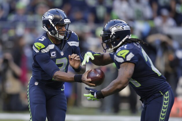 Seattle Seahawks quarterback Russell Wilson hands off to running back Marshawn Lynch, right, in the first half of an NFL football game against the Green Bay Packers, Thursday, Sept. 4, 2014, in Seattle. (AP Photo/Stephen Brashear)