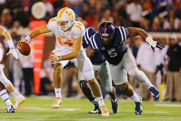Oct 18, 2014; Oxford, MS, USA; Tennessee Volunteers quarterback Justin Worley (14) advances the ball while being chased by Mississippi Rebels defensive tackle Robert Nkemdiche (5) during the game at Vaught-Hemingway Stadium. Mandatory Credit: Spruce Derden-USA TODAY Sports