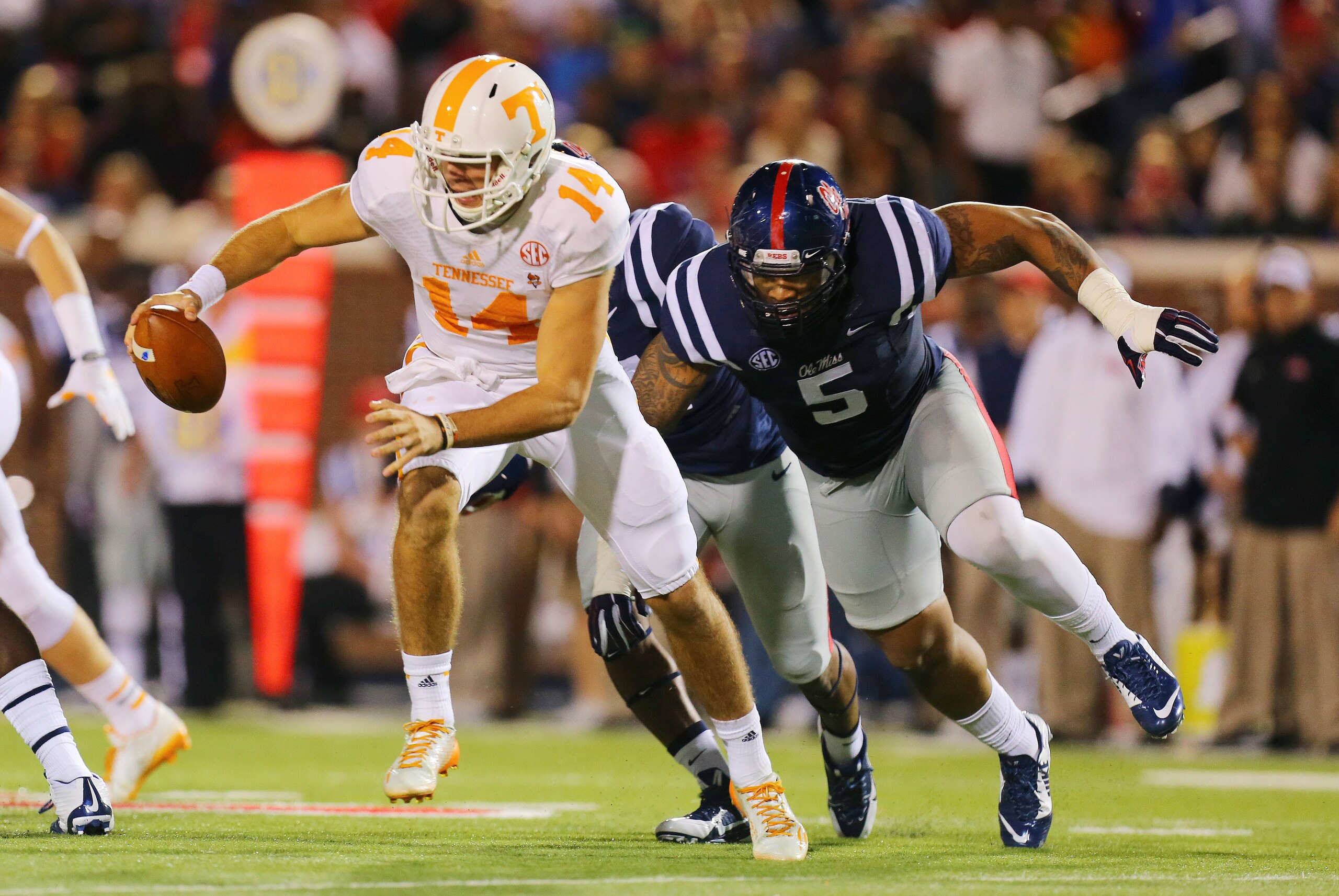 Oct 18, 2014; Oxford, MS, USA; Tennessee Volunteers quarterback Justin Worley (14) advances the ball while being chased by Mississippi Rebels defensive tackle Robert Nkemdiche (5) during the game at Vaught-Hemingway Stadium. Mandatory Credit: Spruce Derden-USA TODAY Sports