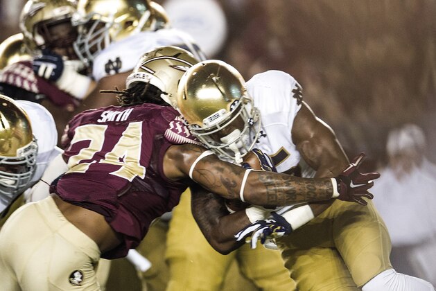 Notre Dame running back  Tarean Folston, right, breaks a tackle-attempt by Florida State linebacker Terrance Smith in the first half of an NCAA college football game in Tallahassee, Fla., Saturday, Oct. 18, 2014. (AP Photo/Mark Wallheiser)