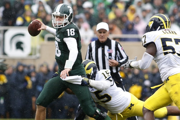 Michigan State quarterback Connor Cook (18) is stopped as he scrambles by Michigan's James Ross III (15) and Frank Clark (57) during the second quarter of an NCAA college football game, Saturday, Nov. 2, 2013, in East Lansing, Mich. (AP Photo/Al Goldis)