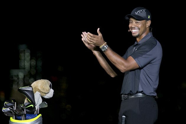 Golfer Tiger Woods applauds as he stands near the golf bag of fellow golfer Rory McIlroy during a golfing demonstration Monday, Aug. 18, 2014, in Jersey City, N.J.  (AP Photo/Mel Evans)