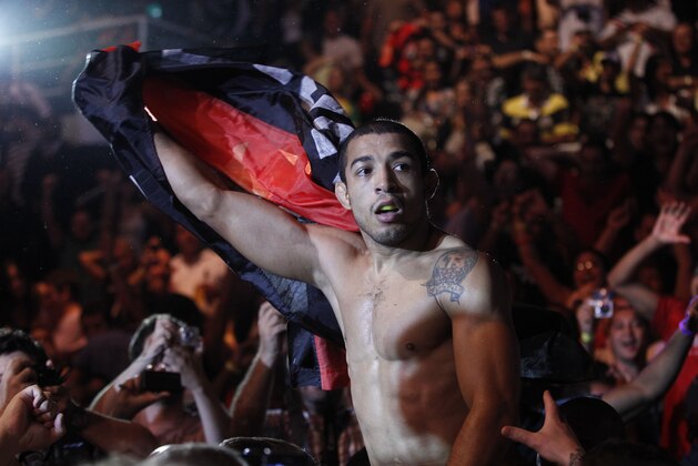 Defending featherweight champion Jose Aldo, from Brazil, celebrates with fans after defeating Chad Mendes, from the US, during their featherweight title bout at the Ultimate Fighting Championship (UFC) 142 in Rio de Janeiro, Brazil, Sunday, Jan. 15, 2012. (AP Photo/Felipe Dana)
