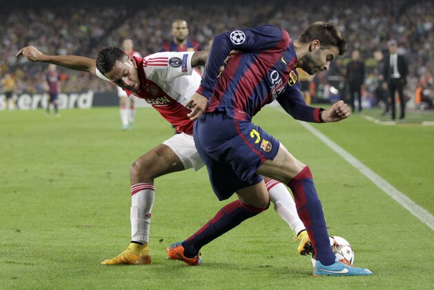 Ajax's Ricardo Kishna, left, challenges for the ball with Barcelona's Gerard Pique during the Champions League group F soccer match between F.C. Barcelona and Ajax at Camp Nou stadium in Barcelona, Spain, Tuesday, Oct. 21, 2014. (AP Photo/Emilio Morenatti)