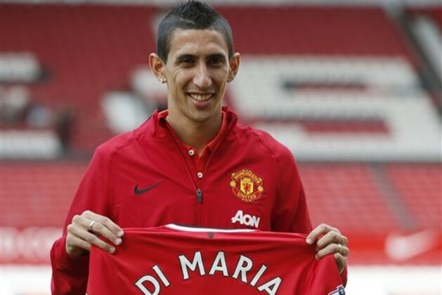 Manchester United's new player Angel Di Maria poses for photographers holding his new shirt, at Old Trafford Stadium in Manchester, England, Thursday, Aug. 28, 2014. Manchester United have signed winger Angel Di Maria from Real Madrid for a British record transfer fee of £59.7m. The Argentine winger had a medical in Manchester on Tuesday and has signed a five-year deal. (AP Photo/Alastair Grant)
