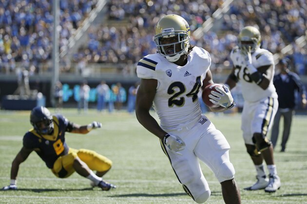 UCLA running back Paul Perkins runs with the ball for a touchdown as California linebacker Jason Gibson, left, looks on during the first quarter of a NCAA college football game Saturday, Oct. 18, 2014, in Berkeley, Calif. At right is UCLA offensive lineman Malcolm Bunche. (AP Photo/Eric Risberg)