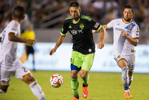 Oct 19, 2014; Carson, CA, USA; Seattle Sounders FC forward Clint Dempsey (2) moves the ball between Los Angeles Galaxy defender A.J. DeLaGarza (20) and Los Angeles Galaxy defender Dan Gargan (33) during seconds half action at StubHub Center. Mandatory Credit: Robert Hanashiro-USA TODAY Sports