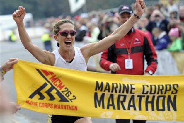 CORRECTION TO REMOVE THE WORD WINNER, AND CHANGE IT TO FIRST FEMALE TO CROSS AND ADD THE NAME OF THE WINNER - Kelly Calway, 29, of Manitou Springs, Co., crosses the finish line to become the first female to cross the finish line during the Marine Corps Marathon in Arlington, Va., Sunday, Oct. 27, 2013. The marathon winds its way through Washington, past numerous monuments, before ending near the Marine Corps War Memorial. Girma Bedada, of Columbia, Ga., won the race. (AP Photo/Cliff Owen)