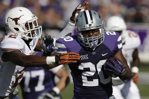 Kansas State running back DeMarcus Robinson (20) is tackled by Texas safety Mykkele Thompson (2) during the first half of an NCAA college football game in Manhattan, Kan., Saturday, Oct. 25, 2014. (AP Photo/Orlin Wagner)