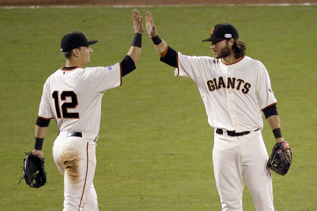 San Francisco Giants' Joe Panik, left, and Brandon Crawford high five after Game 4 of baseball's World Series against the Kansas City Royals on Saturday, Oct. 25, 2014, in San Francisco. The Giants won the game 11-4 to tie the series 2-2.  (AP Photo/Charlie Riedel)
