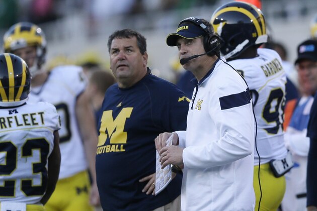 Michigan head coach Brady Hoke, center, and offensive coordinator Doug Nussmeier looks towards the scoreboard during the second half of an NCAA college football game against Michigan State in East Lansing, Mich., Saturday, Oct. 25, 2014. (AP Photo/Carlos Osorio)