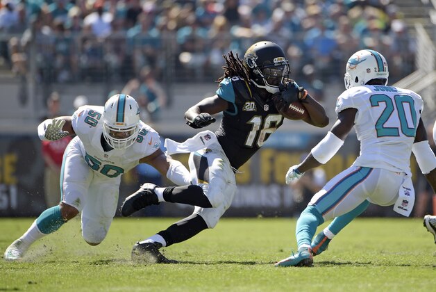 Jacksonville Jaguars running back Denard Robinson (16) tries to get past Miami Dolphins strong safety Reshad Jones (20) and defensive end Olivier Vernon (50) during the first half of an NFL football game in Jacksonville, Fla., Sunday, Oct. 26, 2014. (AP Photo/Phelan M. Ebenhack)
