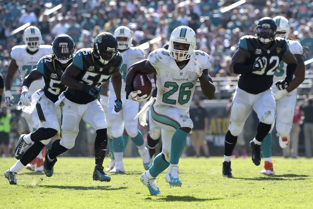 Miami Dolphins running back Lamar Miller (26) breaks free for a 30-yard run past Jacksonville Jaguars outside linebacker J.T. Thomas (52), outside linebacker Geno Hayes (55) and defensive end Ziggy Hood (92) during the second half an NFL football game in Jacksonville, Fla., Sunday, Oct. 26, 2014.(AP Photo/Phelan M. Ebenhack)