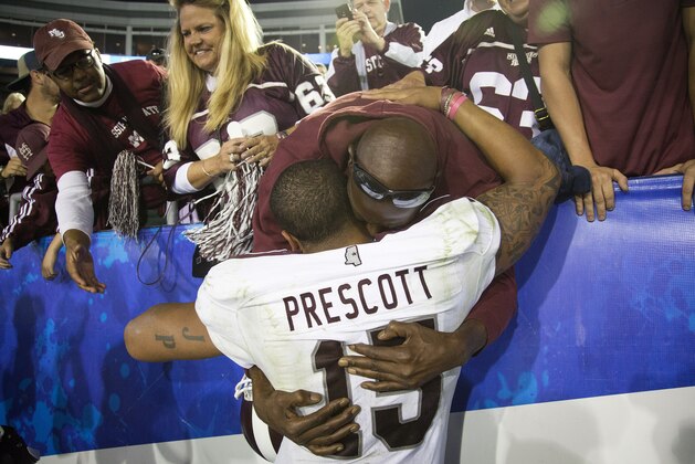 Mississippi State quarterback Dak Prescott hugs his father Nathanial Prescott after Mississippi State defeated Kentucky 45-31 in an NCAA college football game at Commonwealth Stadium in Lexington, Ky., Saturday, Oct. 25, 2014. (AP Photo/David Stephenson)