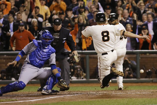Kansas City Royals Salvador Perez misses the throw to home as San Francisco Giants Hunter Pence (8) scores on a two-run RBI double by Juan Perez during the eighth inning of Game 5 of baseball's World Series Sunday, Oct. 26, 2014, in San Francisco. San Francisco Giants Pablo Sandoval, right, also scored on the hit. (AP Photo/Matt Slocum)