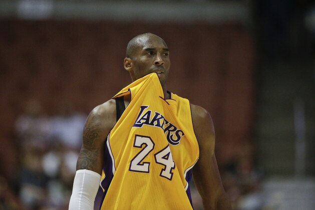 Los Angeles Lakers' Kobe Bryant bites his jersey during the first half of a preseason NBA basketball game against the Phoenix Suns on Tuesday, Oct. 21, 2014, in Anaheim, Calif. (AP Photo/Jae C. Hong)