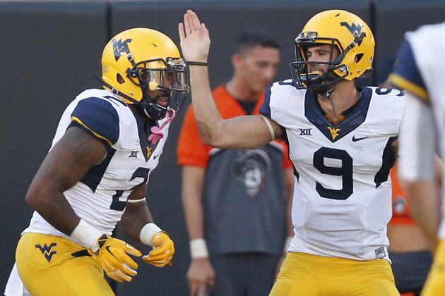 West Virginia quarterback Clint Trickett (9) congratulates Dreamius Smith (2) following his touchdown during the fourth quarter of an NCAA college football game against Oklahoma State in Stillwater, Okla., Saturday, Oct. 25, 2014. West Virginia won 34-10.(AP Photo/Sue Ogrocki)