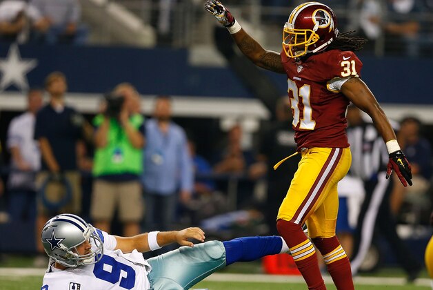 ARLINGTON, TX - OCTOBER 27:  Tony Romo #9 of the Dallas Cowboys is knocked to the ground by Brandon Meriweather #31 of the Washington Redskins during the second half at AT&T Stadium on October 27, 2014 in Arlington, Texas.  (Photo by Tom Pennington/Getty Images)