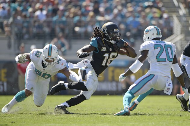 Jacksonville Jaguars running back Denard Robinson (16) tries to get past Miami Dolphins strong safety Reshad Jones (20) and defensive end Olivier Vernon (50) during the first half of an NFL football game in Jacksonville, Fla., Sunday, Oct. 26, 2014. (AP Photo/Phelan M. Ebenhack)
