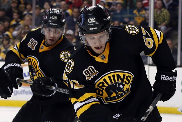 Boston Bruins defenseman Zach Trotman (62) moves to control the puck against Los Angeles Kings left wing Kyle Clifford (13) while Bruins goalie Chad Johnson (30) and defenseman Matt Bartkowski, far left, watch during the third period of an NHL hockey game in Boston, Monday, Jan. 20, 2014. The Bruins won 3-2. (AP Photo/Elise Amendola)