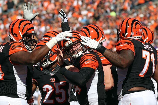 Cincinnati Bengals quarterback Andy Dalton, center, is congratulated by teammates Marshall Newhouse, left, and Andre Smith after scoring a touchdown against the Baltimore Ravens during the first half of an NFL football game in Cincinnati, Sunday, Oct. 26, 2014. (AP Photo/Michael Conroy)