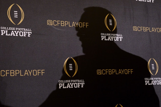The silhouette of Jeff Long, chair of the college football playoff selection committee, is cast upon a backdrop, as he speaks to the media about the first NCAA College Football Playoff rankings during a news conference Tuesday, Oct. 28, 2014, in Grapevine, Texas. The first of seven Top 25 rankings done by a 12-member selection committee was released Tuesday night. (AP Photo/Tim Sharp)