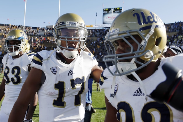 UCLA quarterback Brett Hundley, center, celebrates with wide receiver Alex Van Dyke, leftk, and running back Roosevelt Davis as they leave the field after their 40-37 victory over Colorado in double overtime in an NCAA football game in Boulder, Colo., on Saturday, Oct. 25, 2014. Hundley ran for the winning touchdown. (AP Photo/David Zalubowski)