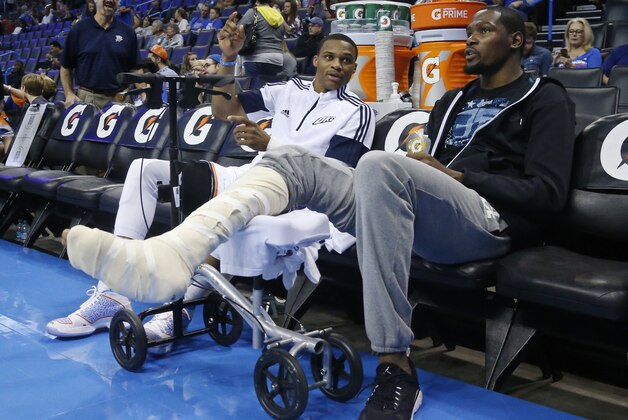 Oklahoma City Thunder guard Russell Westbrook, left, talks with teammate Kevin Durant, right, before the start of a pre-season NBA basketball game against the Utah Jazz in Oklahoma City, Tuesday, Oct. 21, 2014. (AP Photo/Sue Ogrocki)