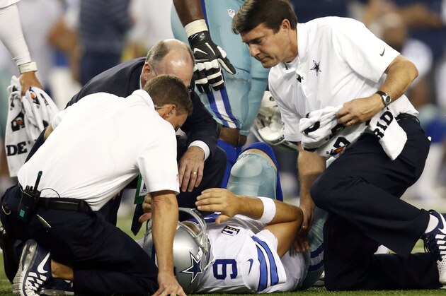 El quarterback de los Cowboys, Tony Romo, en el suelo, es examinado por personal del equipo tras sufrir una lesión en un partido contra Washington el lunes, 27 de octubre de 2014, en Arlington, Texas. (AP Photo/Tim Sharp)