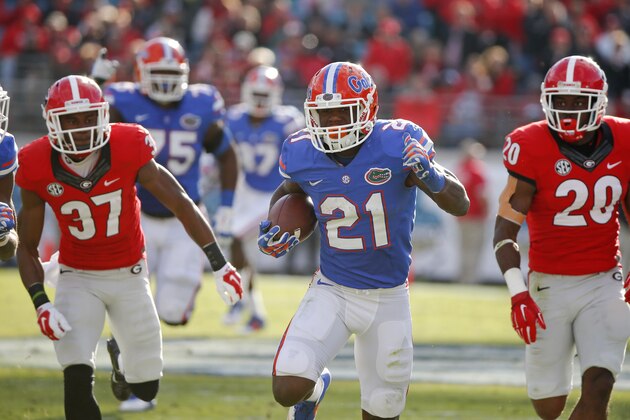 Florida running back Kelvin Taylor (21) runs for yardage past Georgia cornerback Devin Bowman (37) and safety Quincy Mauger (20) during the first half of an NCAA college football game in Jacksonville, Fla., Saturday, Nov. 1, 2014. (AP Photo/Stephen B. Morton)