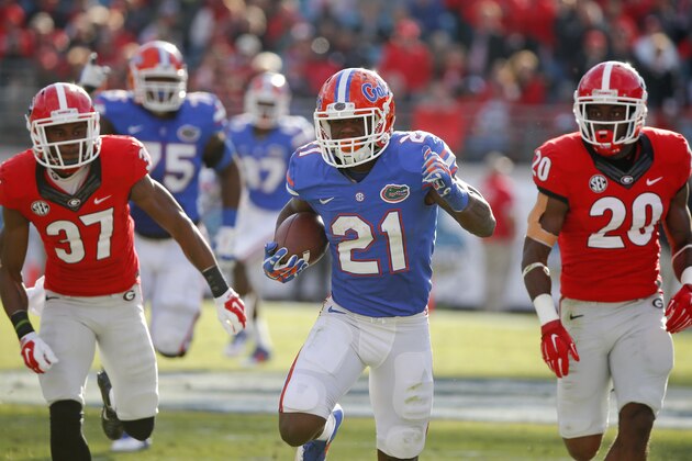 Florida running back Kelvin Taylor (21) runs for yardage past Georgia cornerback Devin Bowman (37) and safety Quincy Mauger (20) during the first half of an NCAA college football game in Jacksonville, Fla., Saturday, Nov. 1, 2014. (AP Photo/Stephen B. Morton)