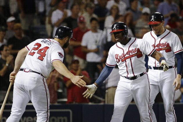 Atlanta Braves' Justin Upton, center, high-fives teammate Evan Gattis, left, after hitting a two-run home run to score Freddie Freeman, right, in the sixth inning of a baseball game against the Miami Marlins, Friday, Aug. 29, 2014, in Atlanta. (AP Photo/David Goldman)