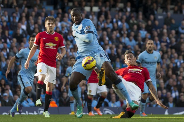 Manchester City's Yaya Toure, centre, is tackled by Manchester United's Marcos Rojo during their English Premier League soccer match at the Etihad Stadium, Manchester, England, Sunday Nov. 2, 2014. (AP Photo/Jon Super)