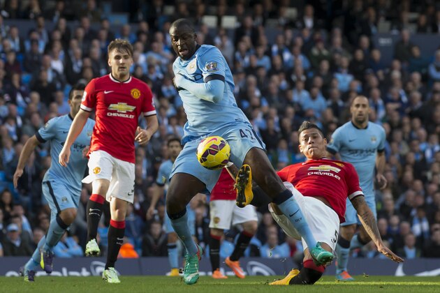 Manchester City's Yaya Toure, centre, is tackled by Manchester United's Marcos Rojo during their English Premier League soccer match at the Etihad Stadium, Manchester, England, Sunday Nov. 2, 2014. (AP Photo/Jon Super)