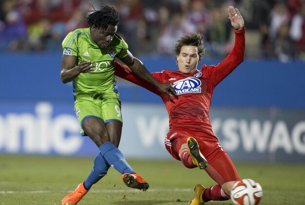 Nov 2, 2014; Dallas, TX, USA; Seattle Sounders FC forward Obafemi Martins (9) shoots on goal while defended by FC Dallas defender Zach Loyd (17) in the first half at Toyota Stadium. Mandatory Credit: Tim Heitman-USA TODAY Sports