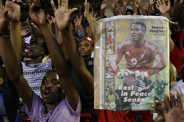 Soccer fans sing as they hold a poster of national soccer captain and goalkeeper Senzo Meyiwa, during a memorial service held for three South African sports figures who died within days of each other at an indoor sports arena in downtown Johannesburg, South Africa, Thursday, Oct. 30, 2014. South Africa's sport ministry organized a combined memorial service for fans of national soccer captain and goalkeeper Senzo Meyiwa, Olympic silver medalist Mbulaeni Mulaudzi and welterweight boxer Phindile Mwelase. (AP Photo/Themba Hadebe)
