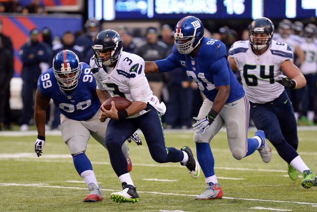 Dec 15, 2013; East Rutherford, NJ, USA; Seattle Seahawks quarterback Russell Wilson (3) runs by New York Giants defensive tackle Cullen Jenkins (99) and defensive end Justin Tuck (91) during the second half at MetLife Stadium. Mandatory Credit: Joe Camporeale-USA TODAY Sports