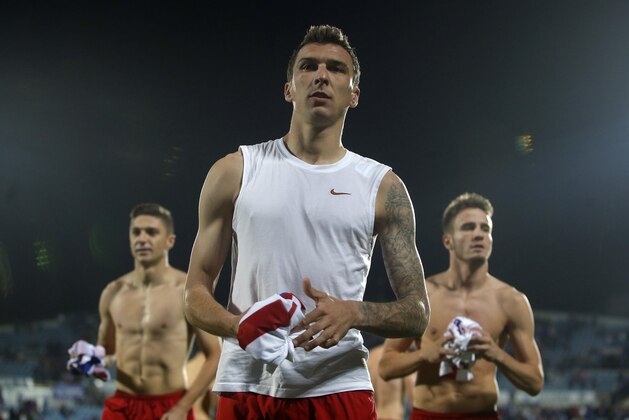 Atletico's Mario Mandzukic, centre, Saul, right, and Atletico's Siqueira, left, offer their t-shirts to the fans during a Spanish La Liga soccer match between Atletico de Madrid and Getafe at the Coliseum Alfonso Perez stadium in Madrid, Spain, Sunday, Oct. 26, 2014. (AP Photo/Andres Kudacki)