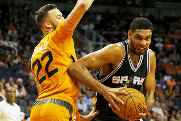 San Antonio Spurs forward Tim Duncan (21) drives past Phoenix Suns center Miles Plumlee (22) in the first quarter during an NBA basketball game, Friday, Oct. 31, 2014, in Phoenix. (AP Photo/Rick Scuteri)