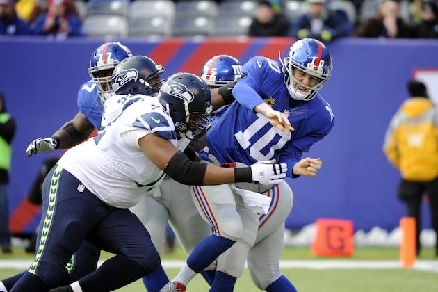 New York Giants quarterback Eli Manning (10) gets hit by Seattle Seahawks' Red Bryant (79) and Brandon Mebane (92) after throwing a pass during the first half of an NFL football game, Sunday, Dec. 15, 2013, in East Rutherford, N.J. (AP Photo/Bill Kostroun)